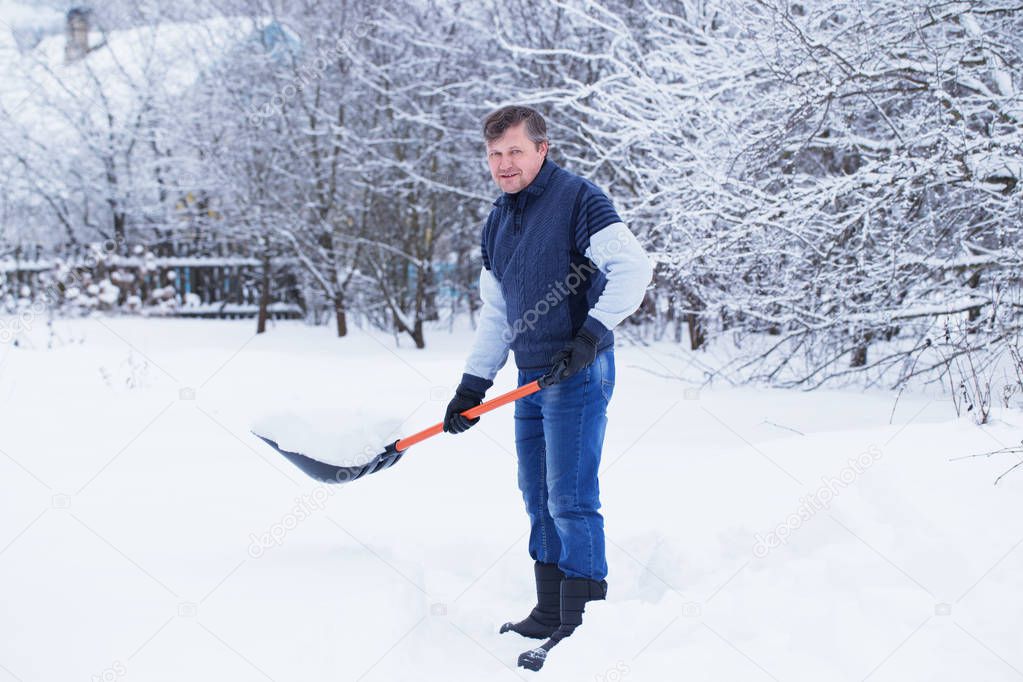 man cleans snow shovel