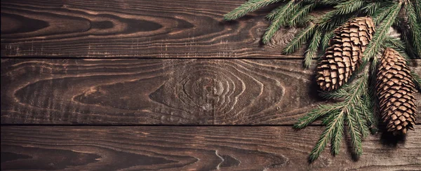 Tannenzweige und Zapfen auf dunklem altem Holzgrund — Stockfoto