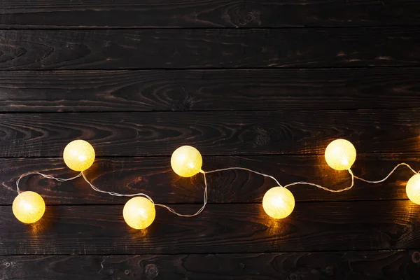 Navidad luces doradas sobre fondo de madera oscura — Foto de Stock