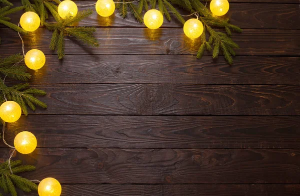 Kerstverlichting met dennenbomen op donkere houten achtergrond — Stockfoto