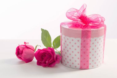 Beyaz arka planda pembe güller olan hediye kutusu