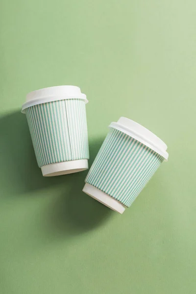 disposable paper cup with coffee on green background