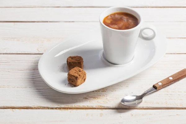 Tasse de café avec bonbons au chocolat sur une vieille table en bois blanc — Photo