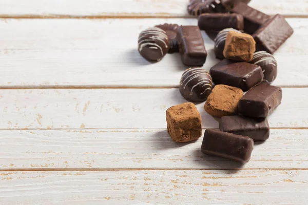 Beyaz ahşap arka plan üzerinde çikolata şeker — Stok fotoğraf