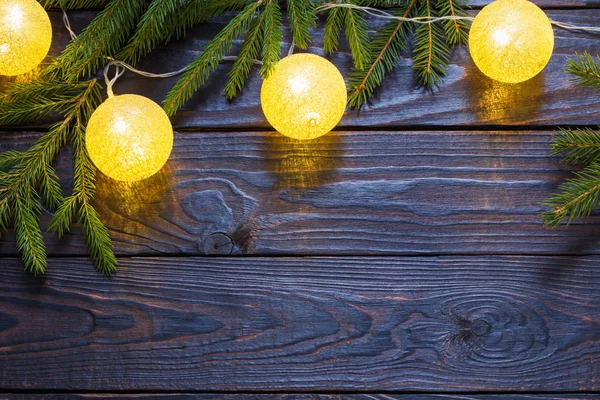 Luzes de Natal com ramos de abeto no fundo de madeira escura — Fotografia de Stock