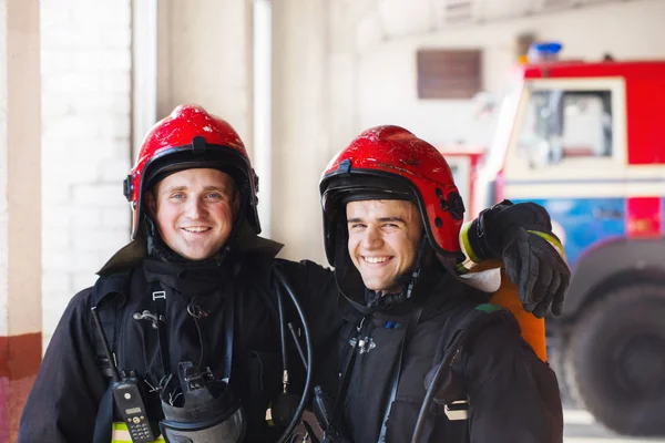 Bomberos jóvenes en el fondo de los camiones de bomberos —  Fotos de Stock