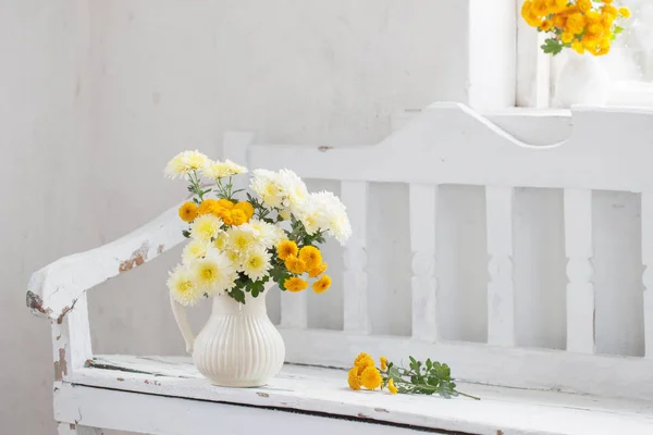 Žluté chryzantémy v džbánu na staré bílé dřevěné lavičce — Stock fotografie