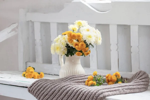 Желтые хризантемы в кувшине на старой белой деревянной скамейке — стоковое фото