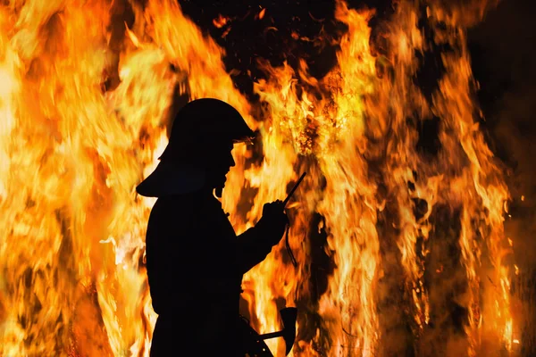 Silueta bombero en el fuego de fondo en la noche —  Fotos de Stock