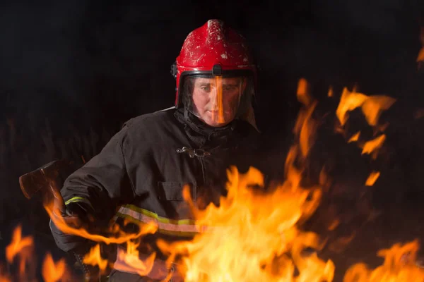 Bombero apaga un fuego por la noche —  Fotos de Stock