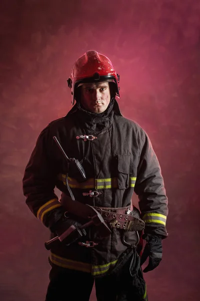 深红色背景下身着制服的消防员画像 — 图库照片