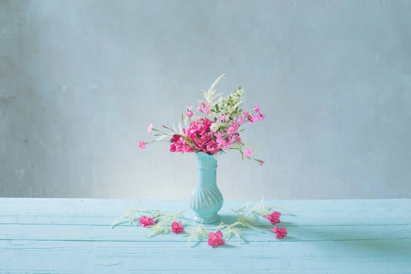 pink flowers in blue vase on blue background