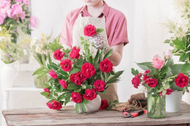 Çiçekçi kız kompozisyon kırmızı güller yapıyor.