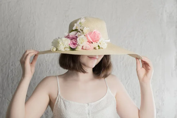 Μελαχρινή Κοπέλα Καπέλο Λουλούδια Στο Φόντο Λευκό Τοίχο — Φωτογραφία Αρχείου