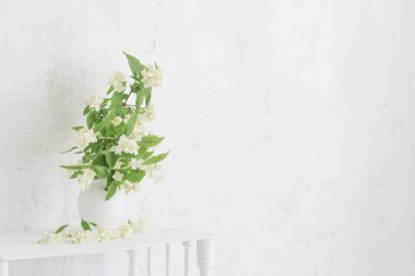 Yasemin çiçekleri arka plandaki eski duvarda vazoda