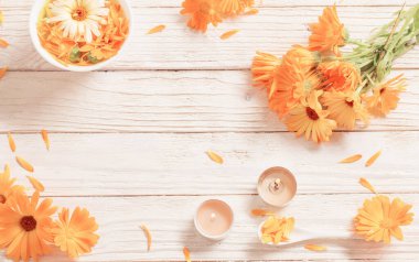 Beyaz ahşap arka planda yanan mumlar ile Calendula tıbbi çiçekler