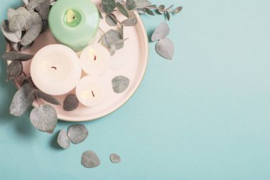 okaliptüs yaprakları ve yanan mumlar mavi arkaplanda