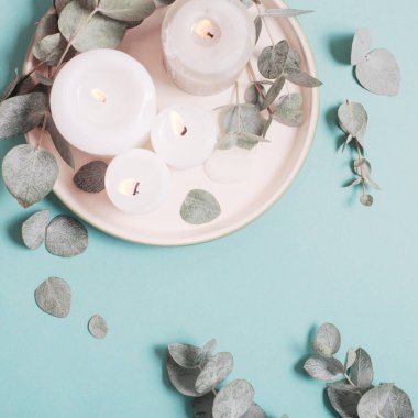 okaliptüs yaprakları ve yanan mumlar mavi arkaplanda