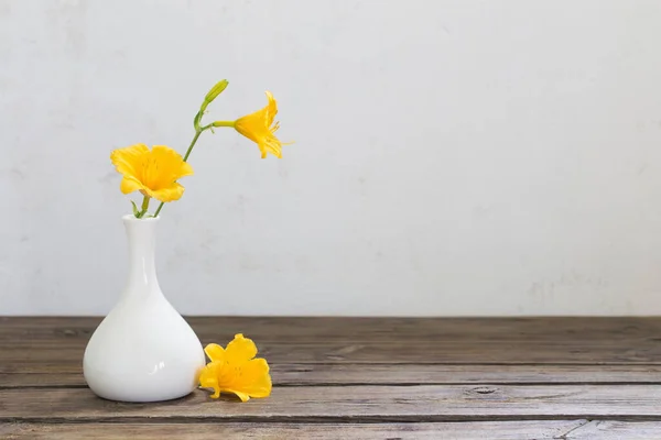 木製のテーブルの上に白い花瓶に黄色の百合の花 — ストック写真