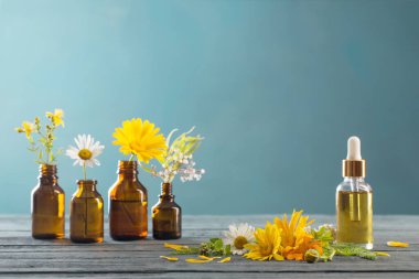 tıbbi bitkiler ve kahverengi şişeler mavi arka planda