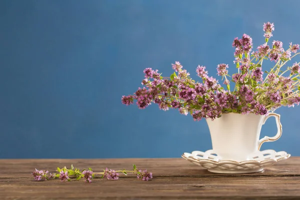 蓝底木制桌子上的白葡萄酒杯百里香花 — 图库照片