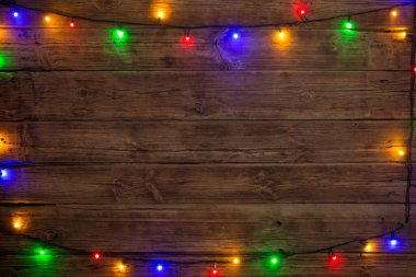 Tahta yüzeyinde çok renkli ampulleri olan elektrik çelengi, Noel ve Yeni Yıl arkaplanı