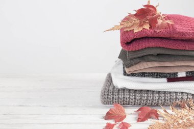 Sonbahar yapraklı kazak yığını beyaz ahşap masada.