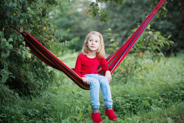 笑顔小さなブロンド女の子でハンモックで庭 — ストック写真