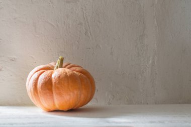 arkaplandaki beyaz duvardaki tahta masada turuncu balkabağı