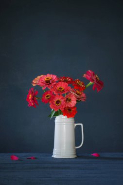 Koyu mavi arka planda beyaz sürahi içinde pembe çiçekler