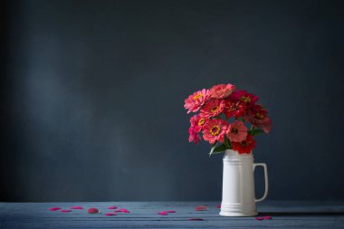 Koyu mavi arka planda beyaz sürahi içinde pembe çiçekler