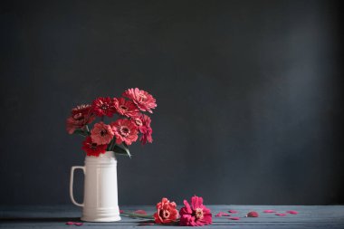 Koyu mavi arka planda beyaz sürahi içinde pembe çiçekler