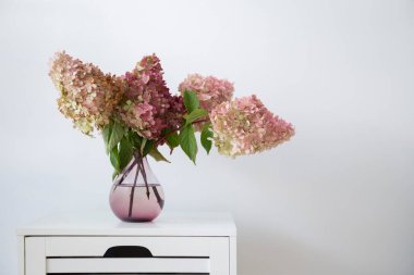 Beyaz odadaki vazoda bir buket ortanca