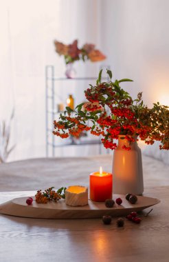 Vazoda yanan mumlarla dolu sonbahar meyveleri.