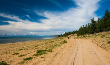 Bisiklet turist dunes Gölü kıyısında kumlu karayoluyla yürüyüş.