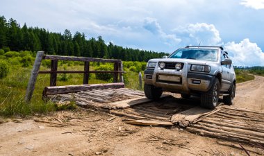 Off-road aracı çakıl engebeli yolda çürümüş küçük ahşap köprü