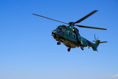Mavi gökyüzü arka plan üzerinde büyük koyu yeşil gezinen askeri helikopter 