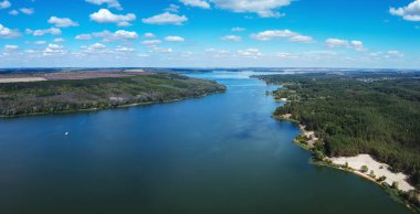 Büyük gölü ve yeşil ormanı olan hava manzarası.