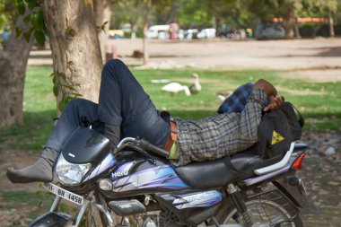 Hindistan, Yeni Delhi - 26 Mart 2018: bir şehirde Park bir motosiklet üzerinde uyku motosikletçi
