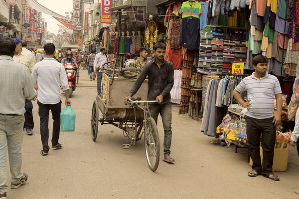 Индия, Нью-Дели - 1 марта 2018 года: Велосипедный грузовой рикша водитель идти в середине рынка улице
