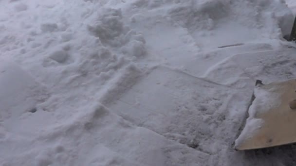 Снегопад в деревне и удаление снега с деревянной лопатой — стоковое видео