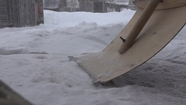 Hóesés a faluban és a hóeltakarítás fa lapáttal — Stock videók