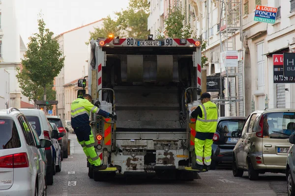 Two refuse collection workers loading garbage into waste truck emptying containers — Stock Photo, Image