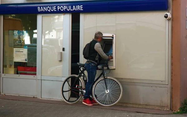 Cyklisten kaserar kortet vid bankomaten — Stockfoto