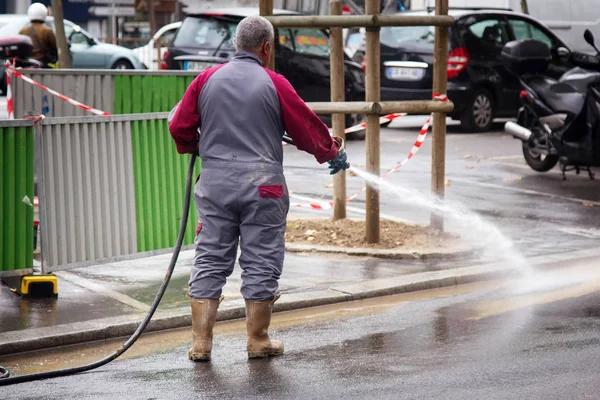 Gatu städning av byggnadsarbetare tvättning med slang — Stockfoto