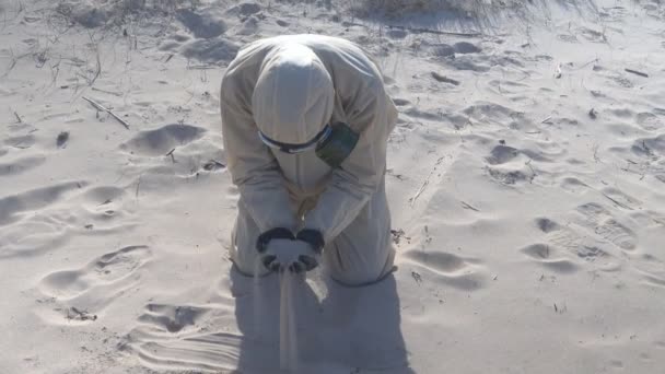 Mężczyzna w kombinezonie ochronnym, maska na plaży morskiej — Wideo stockowe