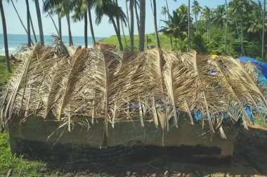 Eski ve yeni mimarinin karışımı. Plastik, palmiye yaprakları ve balık ağıyla kaplı deniz kenarındaki Hint kulübesi..