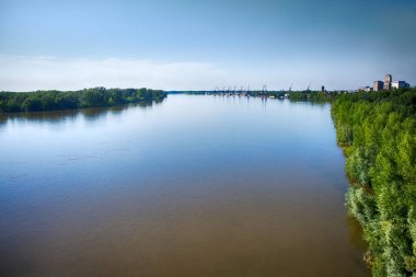 Navigable ovası nehri ve Kuzey Nehri 'ndeki küçük nehir limanı. Kıyılarda söğüt, suda taçlar, parlak yaz güneşi, iskele vinçleri