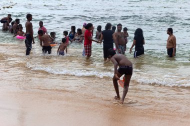 Sri Lanka, Hikkaduwa-11 Aralık 2019: Sinhalese boş günlerinde sığ sularda çırpınıyor. Kadınlar geleneksel terbiye yüzünden dış elbiselerini çıkarmazlar. Lackadiv Denizi