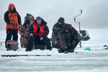 Rusya, Volkhov-24 Şubat 2019: Kışın buzda aktif dinlenme. Balıkçılar Ladoga Gölü 'nde büyük bir balık oltası tutuyorlar.